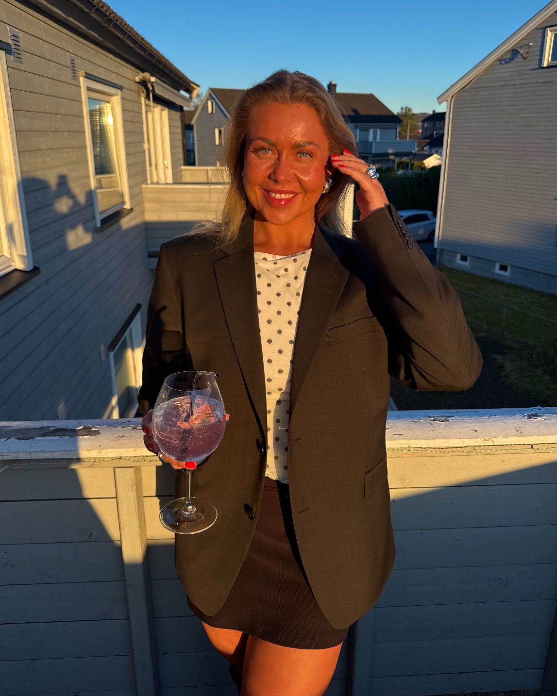 Coachen står utenfor med et vinglass og smiler.