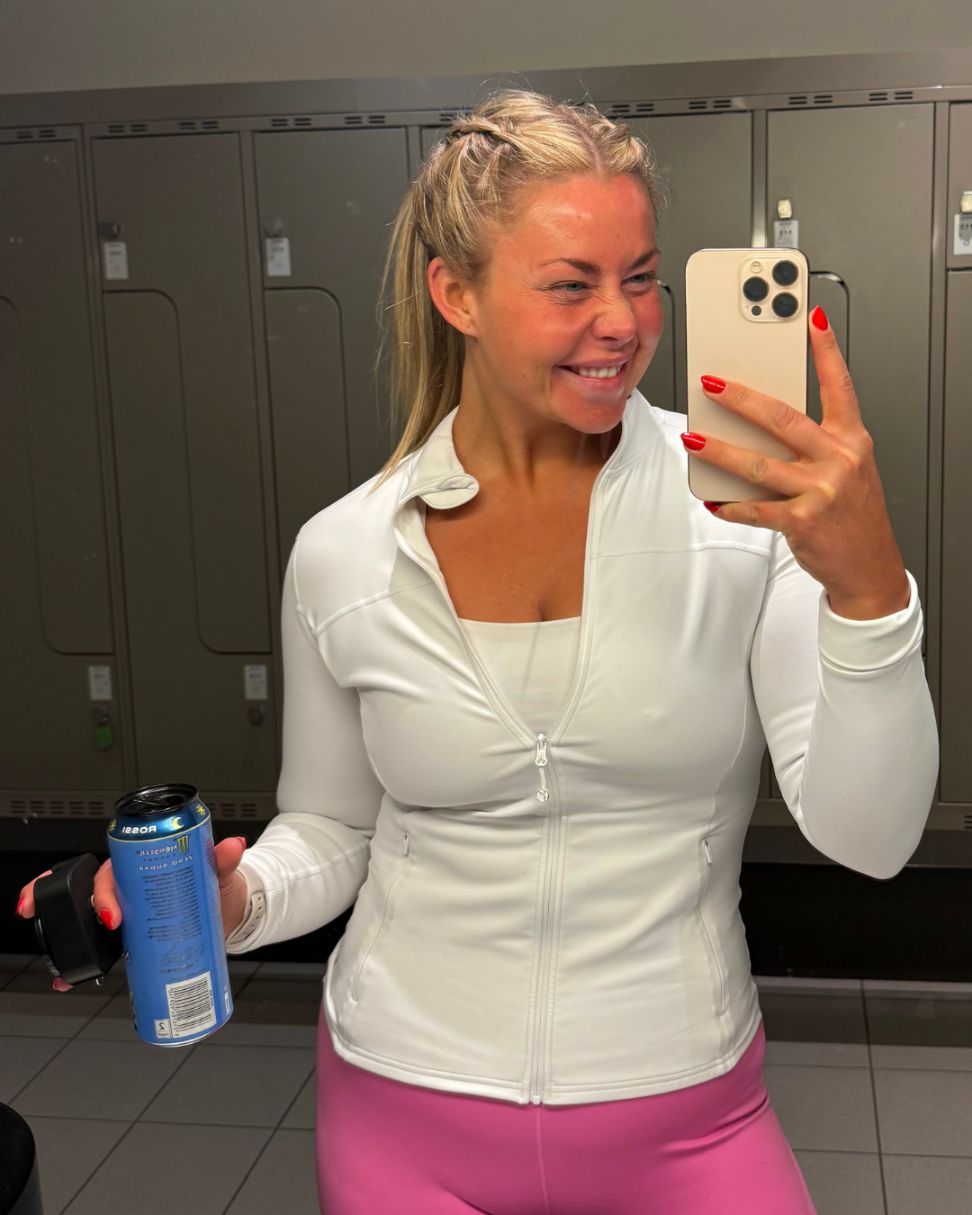 Coachen smiler på en terrasse i kveldssol med et glass i hånden